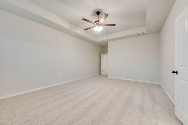 carpeted empty room featuring a raised ceiling and ceiling fan