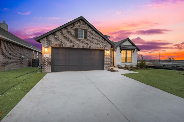 front facade featuring a garage, a lawn, and central air condition unit