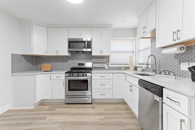 kitchen with sink, tasteful backsplash, light wood-type flooring, stainless steel appliances, and white cabinets