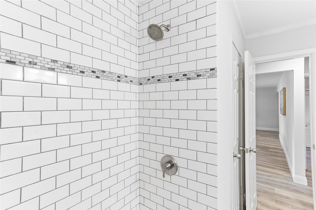 bathroom with crown molding, wood-type flooring, and tiled shower