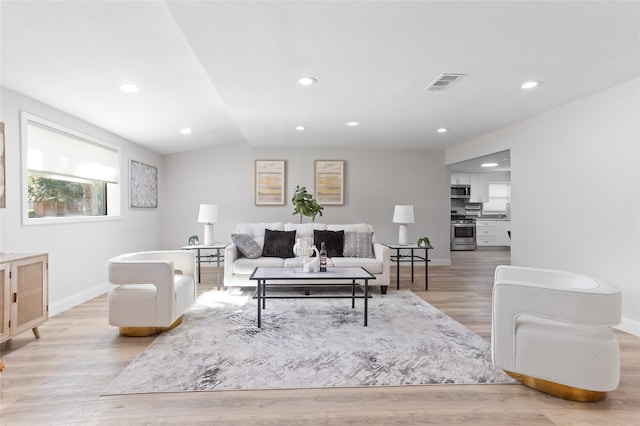 living room featuring lofted ceiling and light hardwood / wood-style flooring