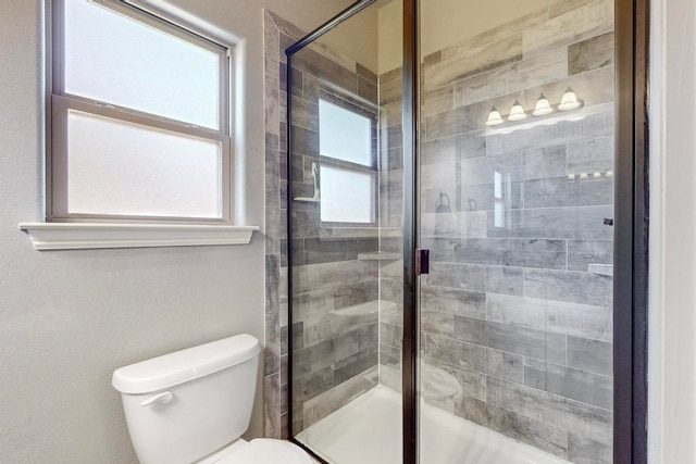 bathroom featuring toilet and a shower with shower door