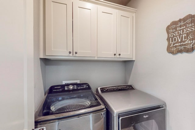 clothes washing area with cabinets and washer and dryer