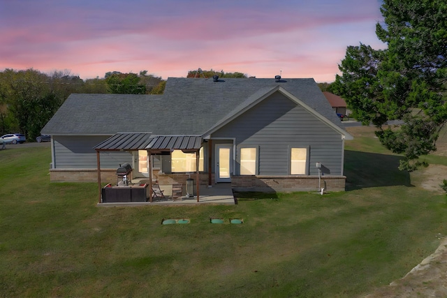 back house at dusk with a lawn and a patio