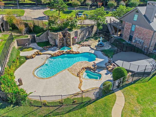 community pool with a yard, a patio, a hot tub, stairway, and a fenced backyard