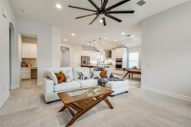 living room featuring vaulted ceiling, light colored carpet, ceiling fan, and sink