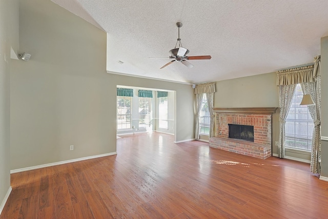 unfurnished living room featuring hardwood / wood-style flooring, ceiling fan, a fireplace, and a textured ceiling