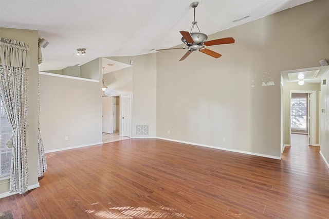 unfurnished living room featuring hardwood / wood-style flooring, ceiling fan, high vaulted ceiling, and a textured ceiling