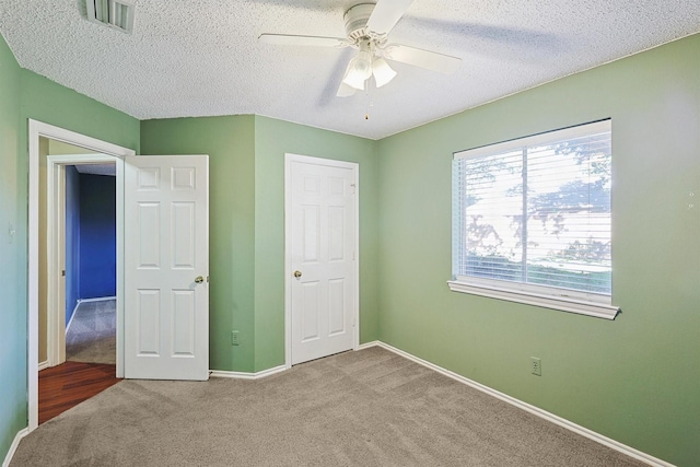 unfurnished bedroom featuring ceiling fan, carpet flooring, and a textured ceiling