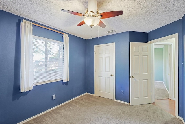 unfurnished bedroom with ceiling fan, a textured ceiling, and carpet flooring