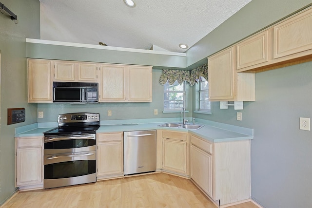 kitchen with lofted ceiling, sink, light hardwood / wood-style floors, stainless steel appliances, and a textured ceiling