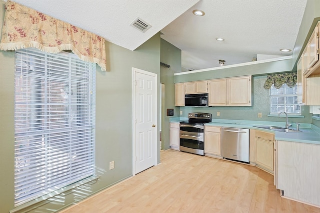 kitchen with lofted ceiling, sink, light hardwood / wood-style flooring, a textured ceiling, and appliances with stainless steel finishes