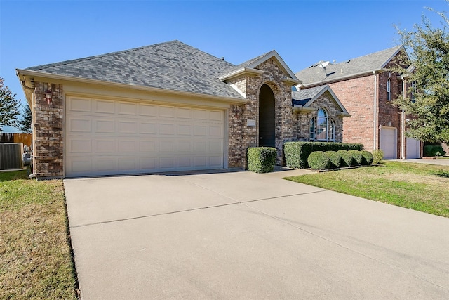 view of front of home featuring a garage, a front yard, and central AC