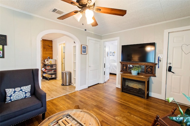 living room featuring a textured ceiling, hardwood / wood-style flooring, and crown molding