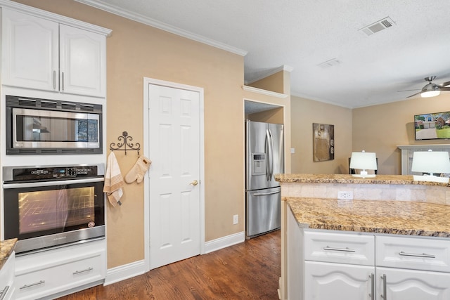 kitchen with appliances with stainless steel finishes, dark hardwood / wood-style flooring, light stone counters, a textured ceiling, and white cabinets