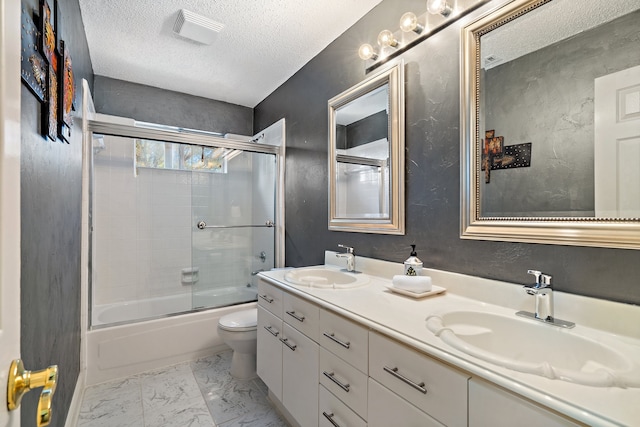 full bathroom featuring toilet, vanity, a textured ceiling, and combined bath / shower with glass door