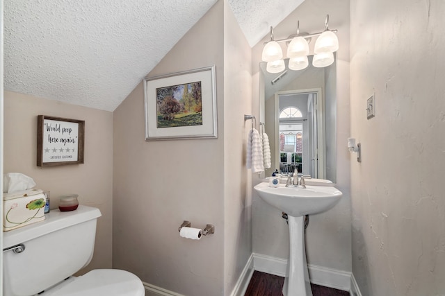 bathroom with wood-type flooring, toilet, lofted ceiling, and a textured ceiling