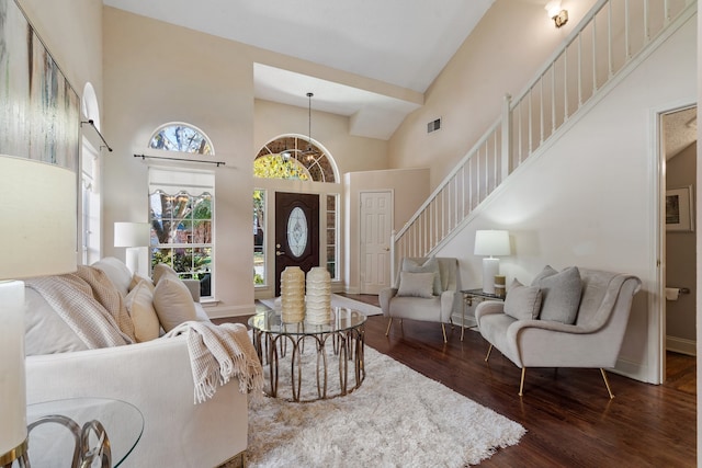 living room featuring dark hardwood / wood-style flooring, high vaulted ceiling, and a notable chandelier