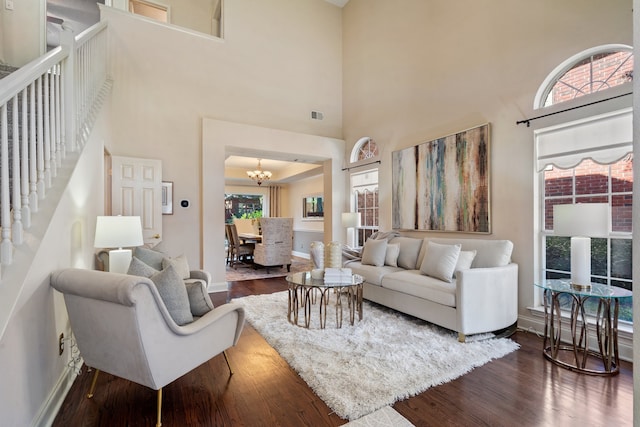 living room featuring hardwood / wood-style flooring, a notable chandelier, and a high ceiling