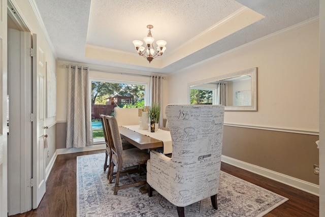 dining area with a chandelier, a raised ceiling, dark wood-type flooring, and crown molding