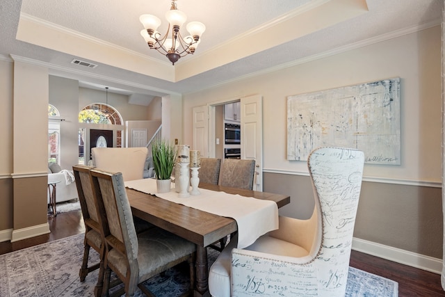 dining space with a raised ceiling, dark hardwood / wood-style floors, an inviting chandelier, and ornamental molding