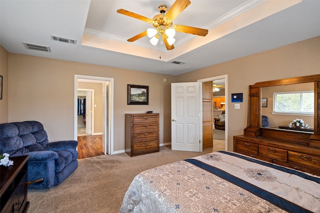 bedroom featuring a raised ceiling, ceiling fan, light colored carpet, and ornamental molding