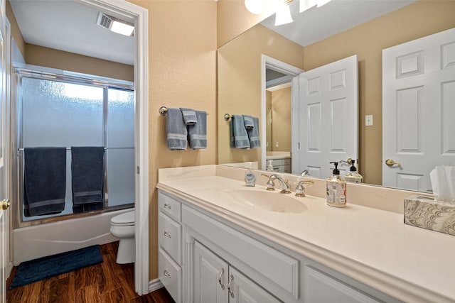 full bathroom with enclosed tub / shower combo, toilet, wood-type flooring, and vanity