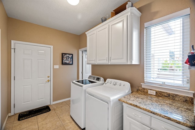 clothes washing area with cabinets, light tile patterned floors, a textured ceiling, and washing machine and clothes dryer