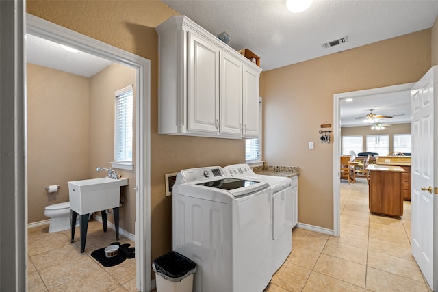 laundry area with cabinets, ceiling fan, light tile patterned floors, a textured ceiling, and washing machine and clothes dryer