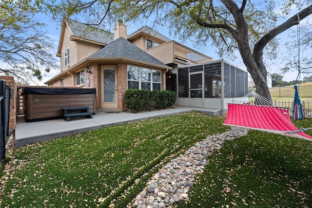 rear view of property with a yard, a hot tub, and a sunroom