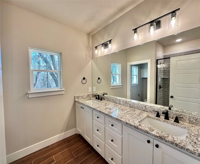 bathroom featuring vanity, a healthy amount of sunlight, a shower with shower door, and hardwood / wood-style flooring