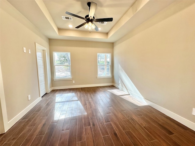 unfurnished room featuring dark hardwood / wood-style floors, ceiling fan, and a tray ceiling