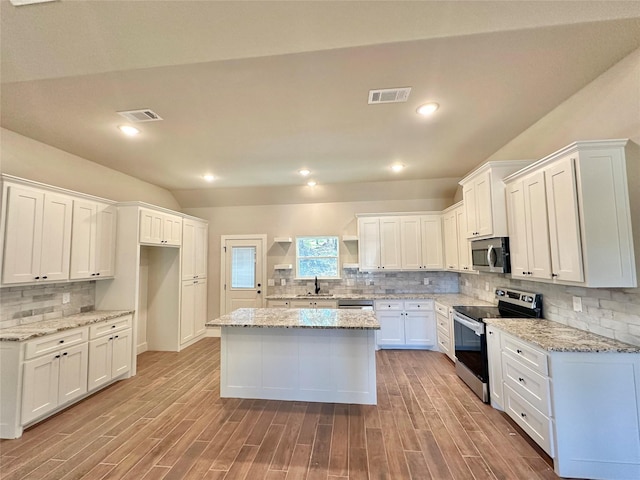 kitchen featuring stainless steel appliances, visible vents, a sink, and open shelves