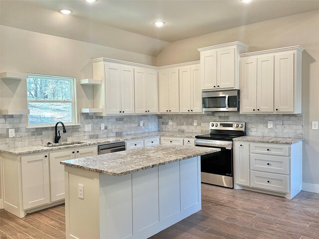 kitchen featuring sink, a kitchen island, hardwood / wood-style floors, white cabinets, and appliances with stainless steel finishes