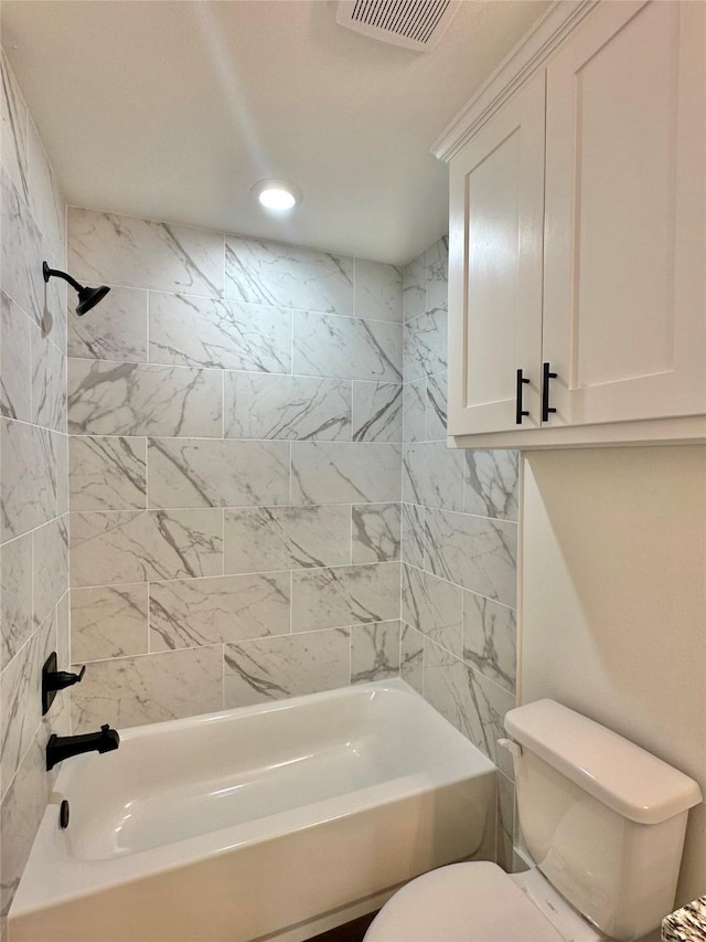 bathroom featuring toilet and tiled shower / bath