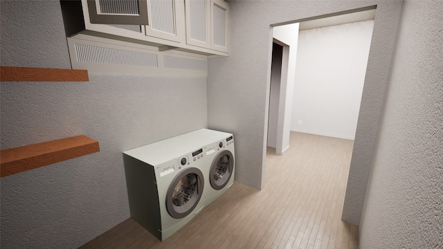 washroom with washing machine and dryer, a textured wall, and wood finished floors