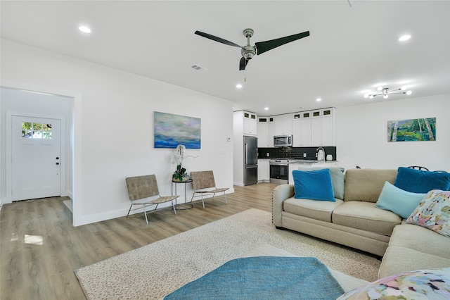 living room featuring ceiling fan and light wood-type flooring