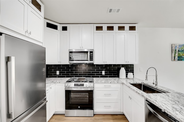 kitchen featuring light stone countertops, white cabinetry, sink, and stainless steel appliances