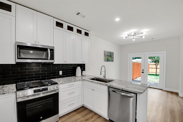 kitchen featuring sink, light hardwood / wood-style flooring, white cabinetry, kitchen peninsula, and stainless steel appliances