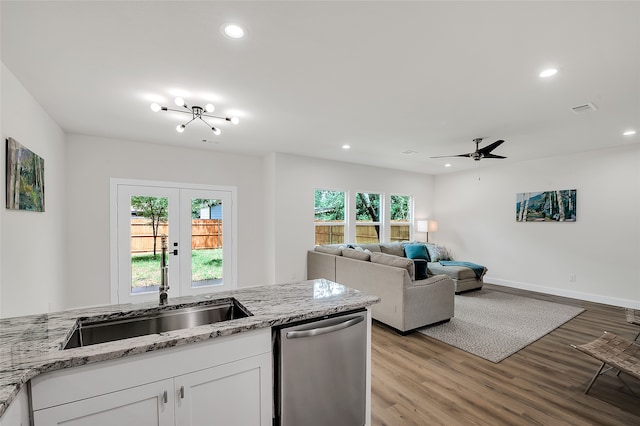 kitchen featuring stainless steel dishwasher, light stone counters, sink, white cabinets, and light hardwood / wood-style floors