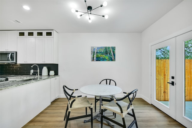 dining space featuring an inviting chandelier, french doors, and light hardwood / wood-style flooring