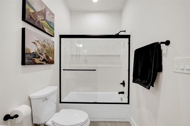 bathroom with tile patterned flooring, toilet, and bath / shower combo with glass door