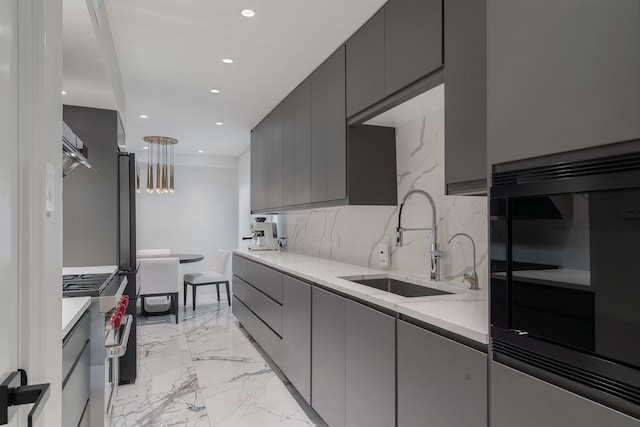 kitchen featuring stainless steel stove, light stone counters, gray cabinetry, and sink