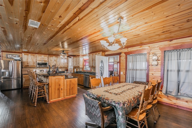 dining room with wooden walls, ceiling fan with notable chandelier, wooden ceiling, and dark hardwood / wood-style flooring