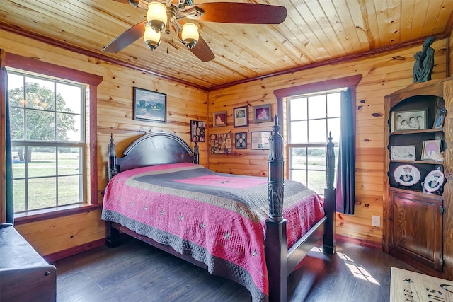 bedroom with multiple windows, dark hardwood / wood-style floors, ceiling fan, and wooden walls