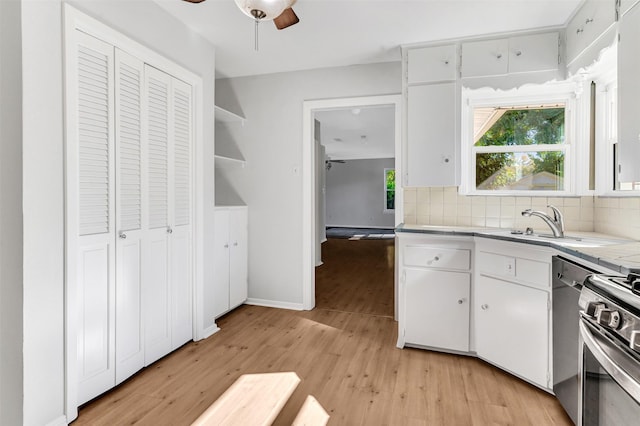 kitchen featuring backsplash, light hardwood / wood-style flooring, white cabinets, and appliances with stainless steel finishes