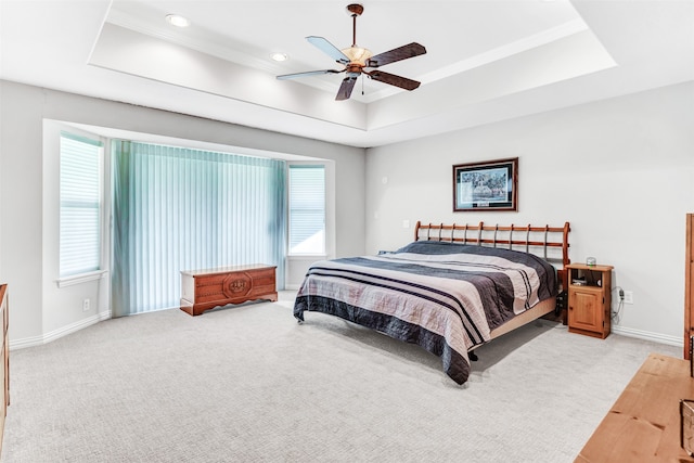 bedroom with ceiling fan, a raised ceiling, and multiple windows