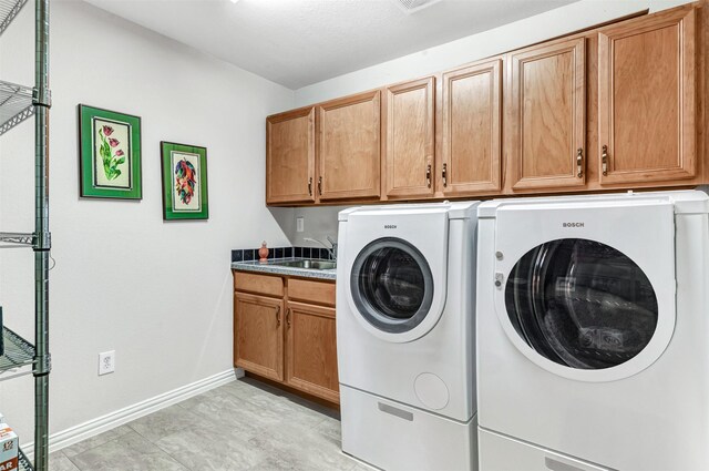 clothes washing area with cabinets, sink, and washing machine and clothes dryer