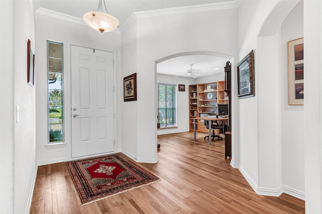 entryway with ceiling fan, wood-type flooring, and crown molding