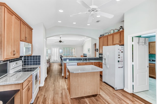 kitchen featuring light stone countertops, kitchen peninsula, vaulted ceiling, white appliances, and light wood-type flooring